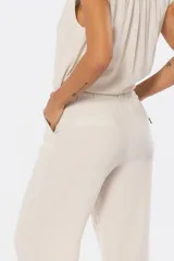 Pantalón de lino color beige con media cintura elastizada, bolsillos laterales y bolsillos decorativos en la parte trasera.