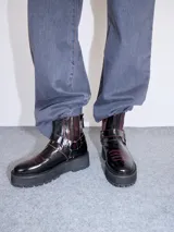 Bota biker negra de caña baja con bordado rojo en la puntera, hebilla metálica lateral y cierre trasero. Plataforma de 5 cm.