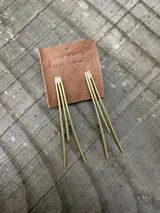 Aretes colgantes largos de bronce, compuestos por tres varillas delgadas y rectas que cuelgan de un soporte superior.