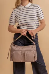 Bandolera de tafeta impermeable, liviana, con dos compartimientos principales, dos bolsillos con cierre y correa regulable con hebilla.