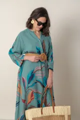 Vestido largo de lino color verde militar con estampado de hojas en tonos azul, naranja y marrón. Tiene cuello mao con botones, mangas tres cuartos y un bolsillo en el pecho.