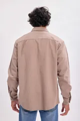 Sobrecamisa color beige con cuello camisero, cierre frontal con botones a presión, dos bolsillos de parche en el pecho y mangas largas con puños abotonados.