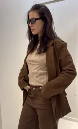 Blazer marrón de gamuza sintética, con solapas de muesca, doble botonadura y forro interior.