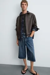 Cazadora bomber de efecto piel color marrón oscuro, con cuello solapa, cierre frontal de cremallera, bolsillos de vivo en cadera y bajo elástico.