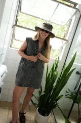 Vestido corto de jean gris con botones frontales, sin mangas, con cuello camisero y bolsillos en el pecho.