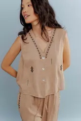 Chaleco color beige de lino con bordados en el cuello y en la parte inferior. Tiene cuello en V y cierre con botones.