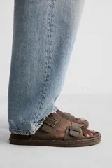 Sandalias marrones de piel con doble tira ancha en el empeine y cierre mediante hebilla. Plantilla con horma anatómica y suela forrada de yute.