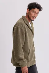 Campera de sherpa verde con cierre frontal y bolsillos laterales.