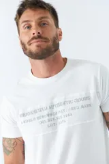 Remera blanca de algodón con cuello redondo y estampado frontal con texto en gris.