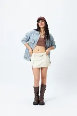 Minifalda color crema con diseño de tablas y cinturón con hebilla.