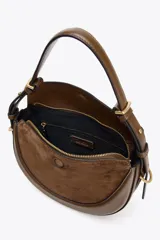 Bolso bandolera ovalado color verde oliva, con solapa de gamuza y asa de cuero ajustable.