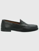 Zapato mocasín de cuero color marrón, con detalle de antifaz y suela de cuero y goma.