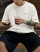 Remera de algodón color crema, corte oversize, con estampado en la espalda que dice "BOHEMIAN DSG®" en letras estilizadas color rosa, y debajo el texto "CERTIFIED AUTHENTIC STREETWEAR".