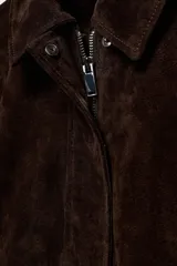 Cazadora de ante 100% piel con cuello solapa, manga larga y bolsillos delanteros de vivo. Presenta cierre frontal con cremallera oculta y botones a presión.