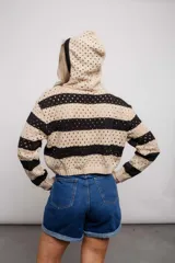 Buzo de punto calado a rayas horizontales en tonos beige y negro, con capucha y corte holgado.