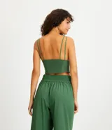 Blusa cropped color verde bosque, con escote en V profundo, tirantes dobles finos y estructura tipo corsé con costuras verticales en el frente.