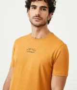 Remera color mostaza de corte slim fit, cuello redondo y manga corta. Presenta un estampado tipográfico en el pecho.
