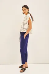Pantalón babucha color mostaza, con elástico en la cintura y cordón ajustable con terminaciones metálicas. Tiene bolsillos diagonales en el frente y falsos bolsillos ojal en la espalda.