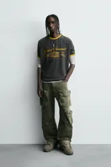 Camiseta de manga larga gris con cuello redondo y ribete amarillo. Estampado frontal con texto "Heavy Transport".