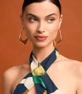 Blusa sin mangas con escote halter, estampado de follaje en tonos verde, azul y beige, y cinturón marrón.
