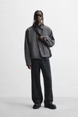 Cazadora relaxed fit color gris oscuro, confeccionada en tejido técnico repelente al agua. Tiene cuello solapa de cuero negro, manga larga con puños ajustables, bolsillos de vivo en la cadera, bolsillo interior, bajo ajustable con cordón y cierre frontal con cremallera oculta por solapa con botones.