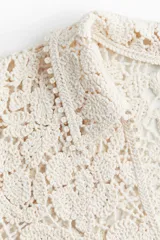 Top color crudo de crochet con cuello camisero, cierre frontal con botones y mangas 3/4.