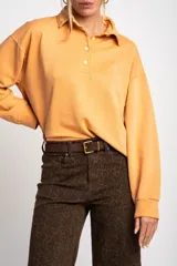 Sweater color naranja con cuello polo y botones, de corte holgado y mangas largas.