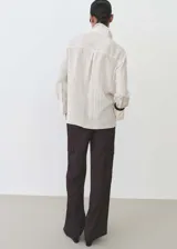 Camisa celeste con rayas verticales finas, de tejido fluido, manga larga abotonada, cuello camisero y corte recto.