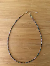 Collar corto de cuentas de turmalina multicolor facetadas, con detalles de cuentas doradas y cierre de mosquetón dorado con cadena de extensión.