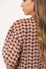 Camisa de gasa estampada traslúcida con diseño geométrico de rombos en tonos lila, naranja y negro. Tiene calce liviano y fluido, abotonado frontal y volado en la cartera.