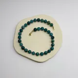 Collar de cuentas esféricas de ágata azul de 10mm, con separadores de hilo rosado y cierre de mosquetón dorado.
