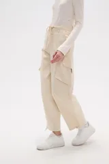 Pantalón cargo de jean color beige, de calce bajo, con bolsillos laterales y cordón ajustable en la cintura.