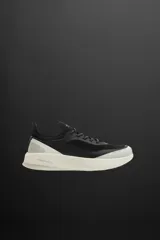 Zapatilla deportiva negra con detalles en gris y blanco, para uso diario y carreras ligeras. Parte superior de tejido de punto transpirable, puntera y talón con material Shield Protect Max, ajuste con cordones, tirador trasero, plantilla OrthoLite® extraíble, entresuela Spume Foam V3 y suela de goma.