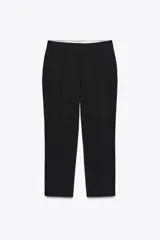 Pantalón negro tobillero de tiro alto con bolsillos delanteros y traseros. Tiene abertura lateral en el bajo y cierre frontal con cremallera y botón.