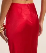 Vestido largo de satén color crema, con escote halter, espalda descubierta y abertura frontal. Presenta detalles de pedrería en el escote.