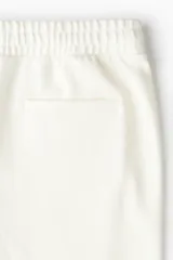 Pantalón jogger color crudo, de corte slim fit, confeccionado en sarga. Presenta cintura elástica con cordón ajustable, bolsillos laterales al bies y bolsillos traseros insertados.