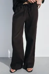 Pantalón palazzo color ladrillo confeccionado en lino 100%, de tiro medio con cintura ajustable con cordones, bolsillos laterales ocultos en costura y pierna ancha.