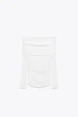 Camiseta blanca de algodón con escote recto, hombros descubiertos y mangas largas. Presenta detalle de frunces en el frente.