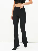 Calza negra de tiro alto, ajustada al cuerpo, con textura acanalada y corte acampanado en el tobillo.