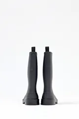 Bota de lluvia negra de caña media, con suela plana y detalle de tira en la parte superior trasera.