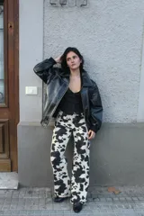 Chaqueta negra de cuero sintético con costuras blancas en contraste, cuello clásico y cierre frontal con botones a presión.