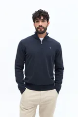 Sweater de tejido liso color verde oscuro, con cuello medio y cierre frontal parcial plateado. Presenta puños y cintura acanalados, y un pequeño logo bordado en el pecho.