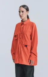 Camisa naranja de manga larga, estilo técnica con múltiples bolsillos delanteros y un bolsillo en la parte inferior de espalda, botones en cartera y mangas, calce oversize.