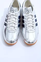 Championes Adidas SL 72 plateados con detalles en azul marino y suela de goma marrón.