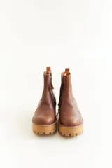 Botas cortas de cuero color marrón y beige, con elástico lateral y suela track color negro.