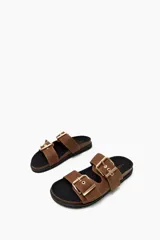 Sandalias planas color tostado con dos tiras anchas sobre el empeine, cada una ajustable con hebillas metálicas doradas.
