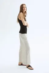 Pantalón ancho de tiro alto con elástico en la parte posterior de la cintura y cierre oculto con corchete en un lado. Bolsillos laterales discretos y piernas amplias con pliegues adelante y atrás. Diseño a rayas verticales grises y blancas.