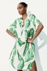 Vestido túnica corto de viscosa con estampado de hojas verdes, cuello mao con abertura en V, mangas cortas, corte holgado y tajos laterales.