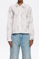 Camisa blanca con estampado de cactus en color gris, corte boxy, cuello camisero, manga larga con puño y cierre frontal con abotonadura.