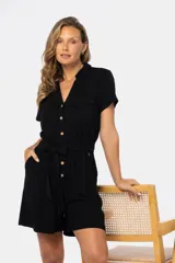 Mono corto negro de lino con cuello camisero, cierre frontal con botones de madera, bolsillos laterales y cinturón del mismo tejido.